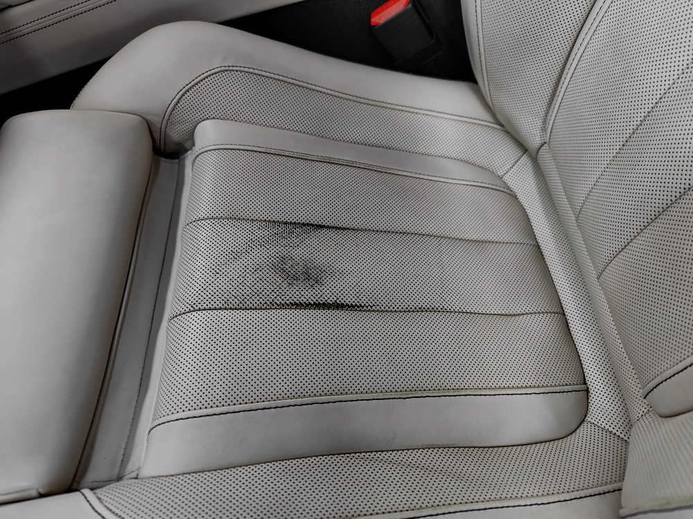 Originalaufnahme des hellen BMW-Ledersitzes mit dunklen Spuren auf der Sitzfläche.