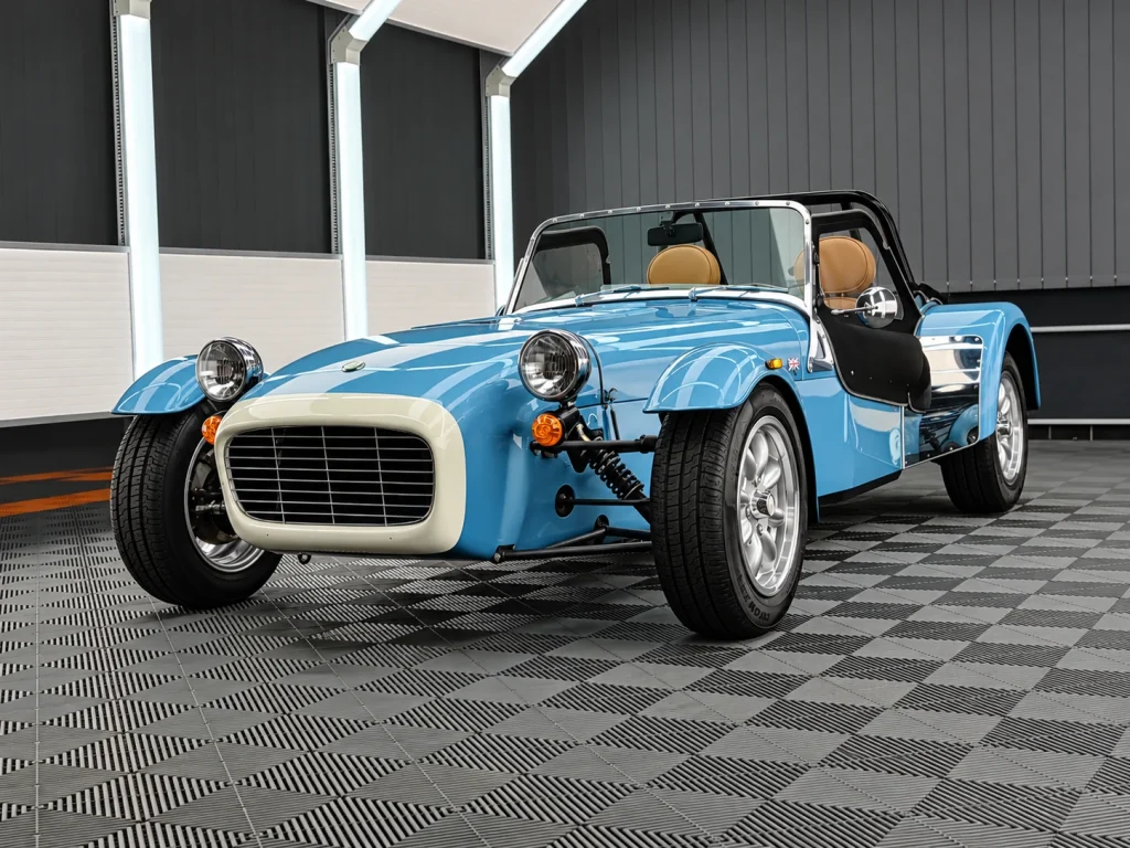 Hellblauer Caterham Super Seven mit silbernen Felgen und beigefarbenen Sitzen im Lichttunnel von Car and Valet.