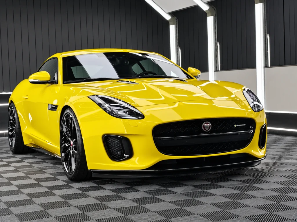 Gelber Jaguar F-Type im Lichttunnel von Car and Valet, schräg von vorn.