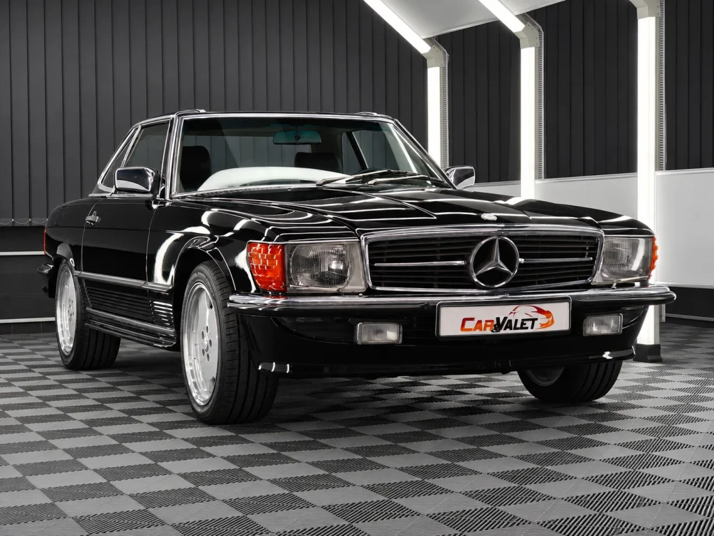 Schwarzer Mercedes-Benz 500 SL R107 mit Hardtop und Chromdetails im Lichttunnel von Car and Valet.
