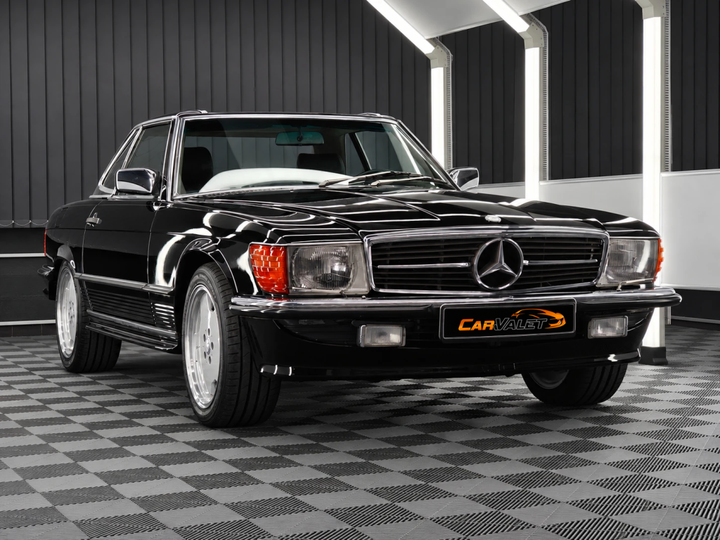 Schwarzer Mercedes-Benz 500 SL R107 mit Hardtop und Chromdetails im Lichttunnel von Car and Valet.