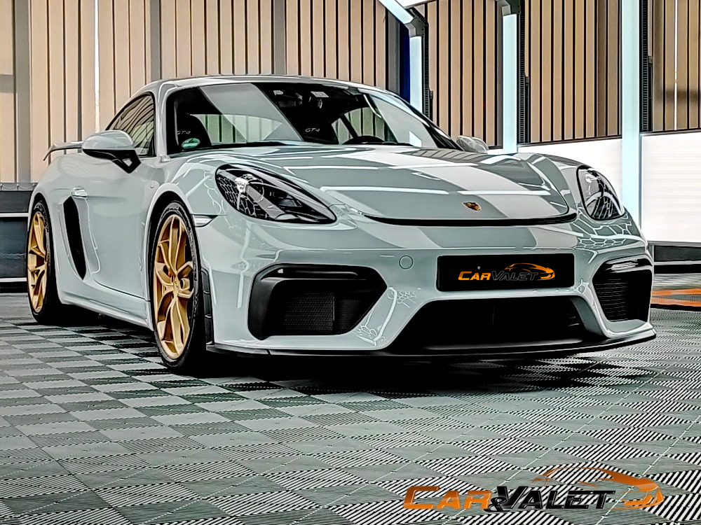 Weißer Porsche Cayman GT4 mit goldfarbenen Felgen im Lichttunnel.